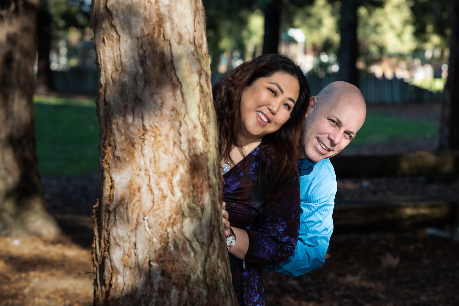 SF Peninsula and South Bay Public Notaries Doug Olive and Julie Tran stand next to a tree smiling. 